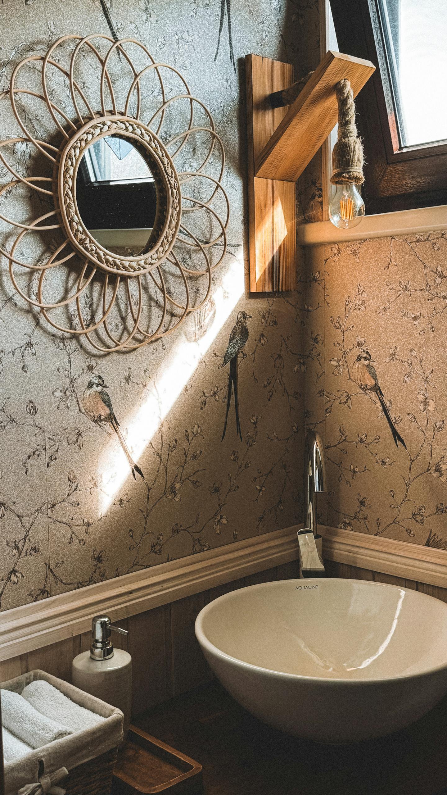 A cozy rustic bathroom featuring a wicker mirror, wall decor, and natural light.