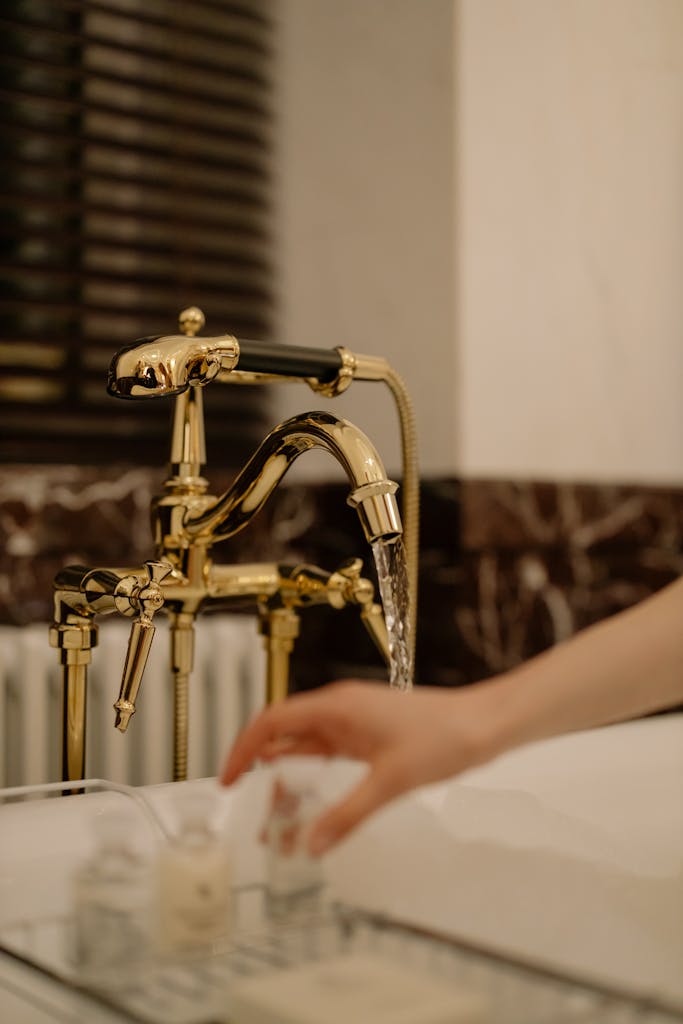 Close-up of a luxurious gold faucet with running water in a modern bathroom setting.