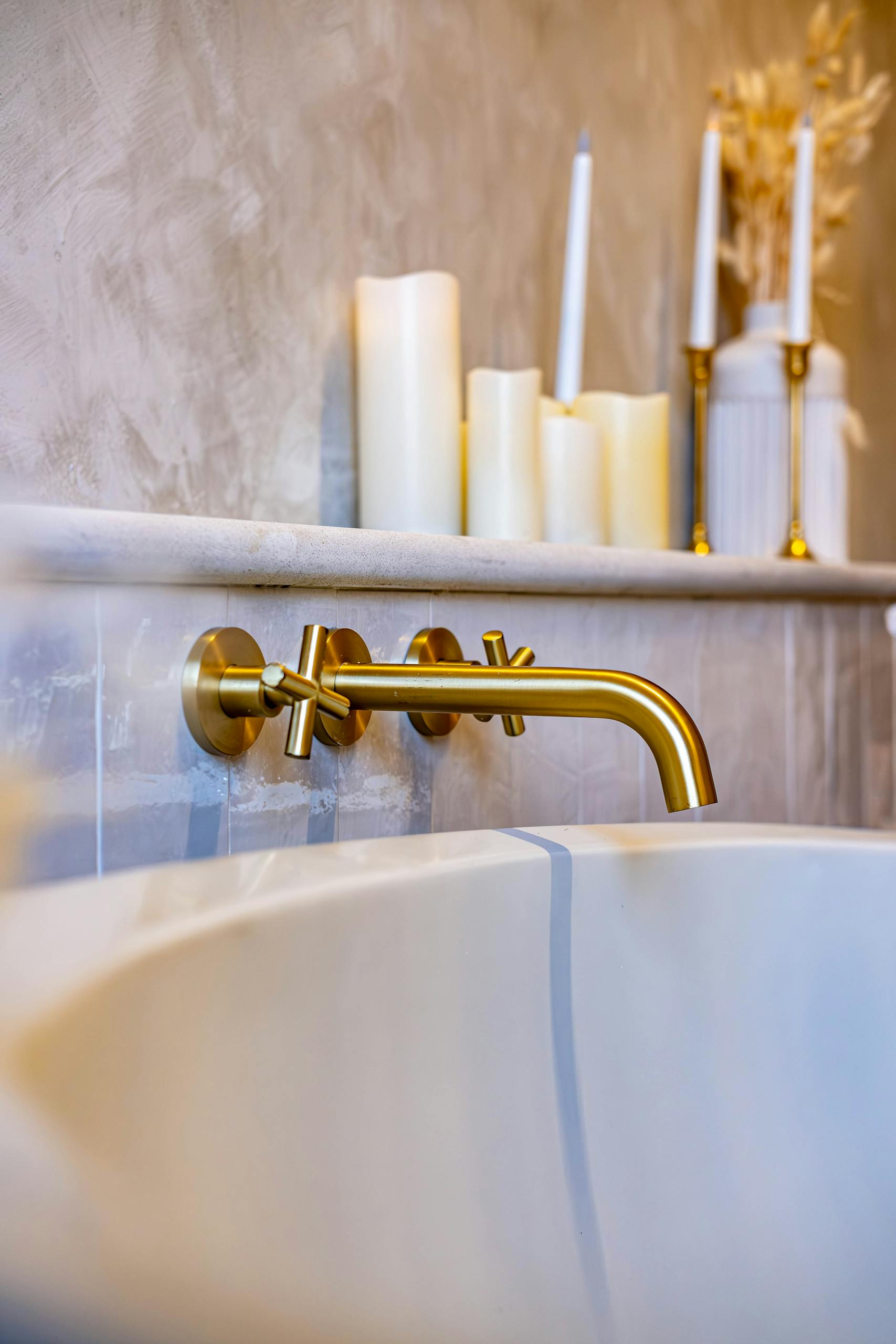 Elegant gold faucet with candles in a serene modern bathroom ambiance.