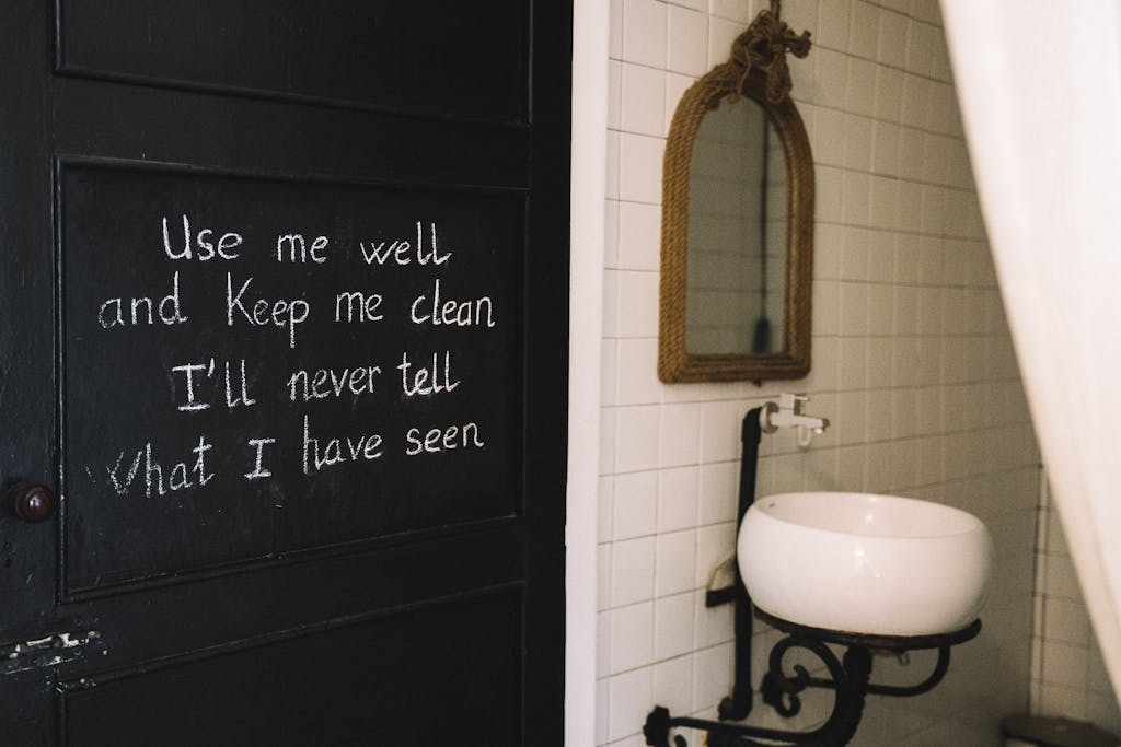 Rustic bathroom interior featuring chalkboard quote and vintage mirror.